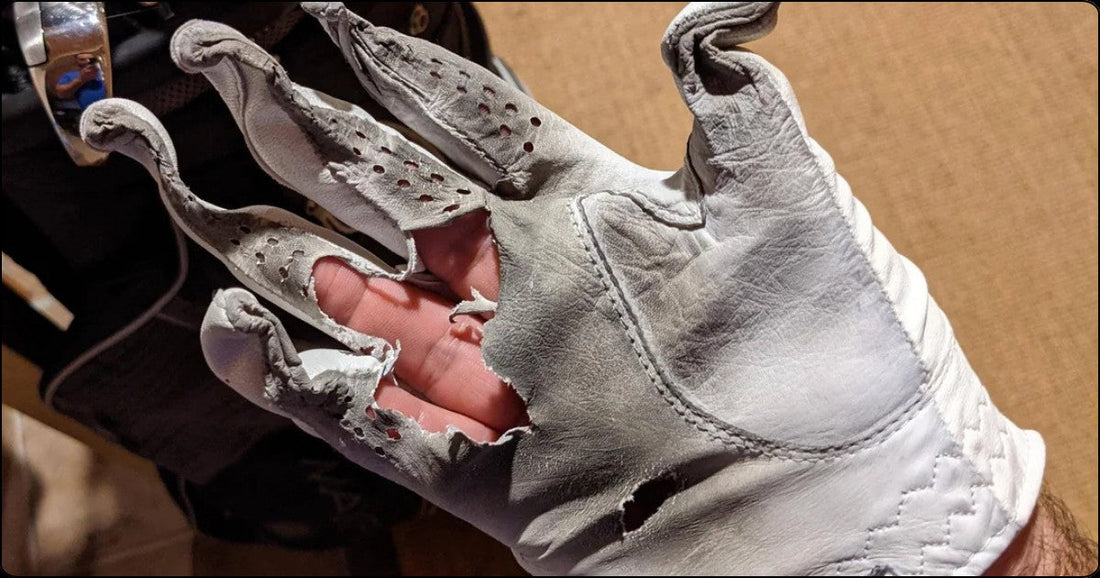Worn out leather golf glove with torn fingers showing advanced grip degradation after heavy use