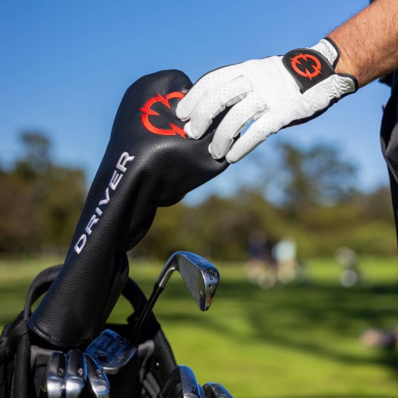 Golfer reaching into bag to grab driver wearing EXO Golf Glove red colorway with red EXO logo on wrist strap