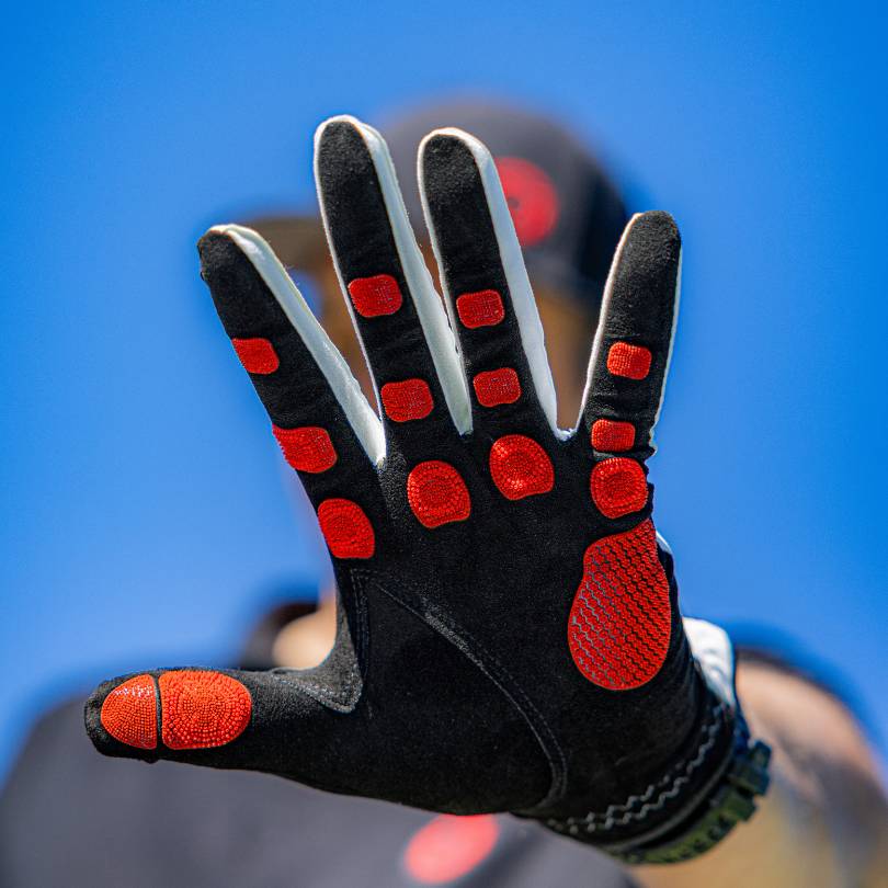 EXO Golf Glove red colorway palm facing forward showing full Zyntech™ nanocell grip zone layout against blue sky