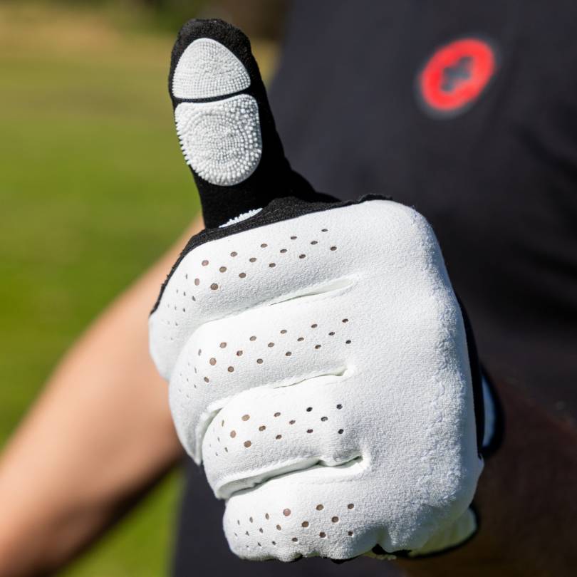 Golfer giving thumbs up wearing EXO Golf Glove white colorway showing Zyntech™ nanocell texture on thumb pad
