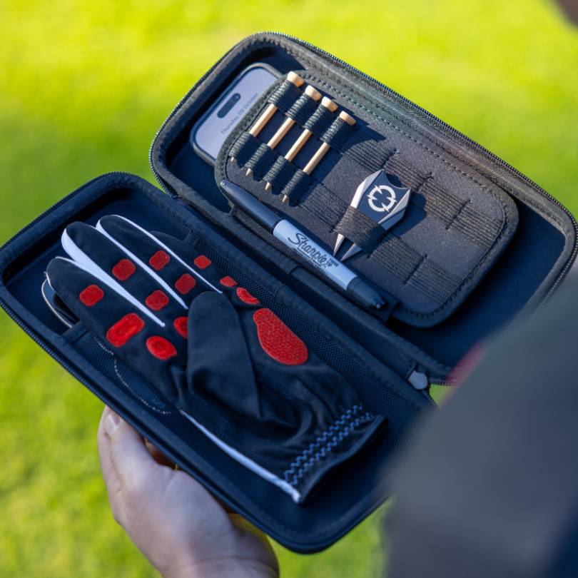 EXO Golf glove case open showing EXO Golf Glove red colorway stored alongside phone tees ball marker and Sharpie in organized compartments