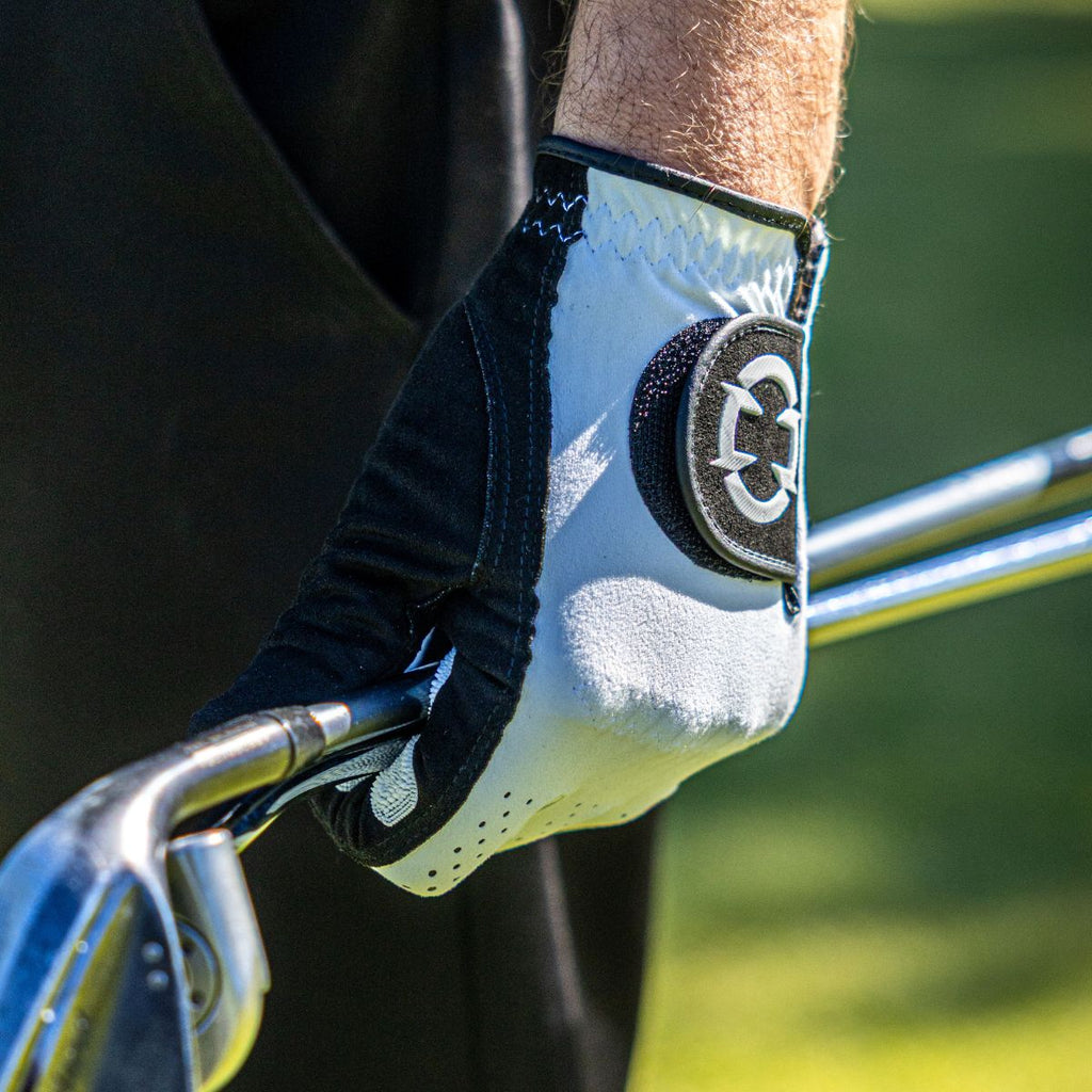 EXO golf glove with white logo holding two golf clubs